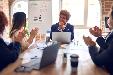 Group of business workers smiling happy and confident in a meeting. Working together looking at presentation using board and laptop applauding at the office.