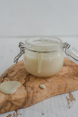 Delicious condensed milk in a jar on an olive tree board.