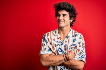 Young handsome man on vacation wearing summer shirt over isolated red background looking to the...