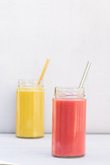 Yellow Banana, pear and red apple, raspberry smoothie. Glass, jar, metal straw.  Health, vegetarian, vegan breakfast, drink. No plastic, Ecology. Grey background, copy space. Vertical. 