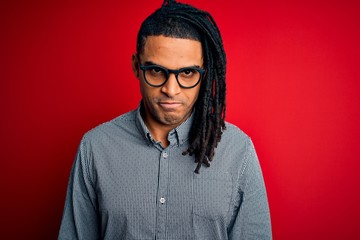 Young handsome african american man with dreadlocks wearing casual shirt and glasses skeptic and nervous, frowning upset because of problem. Negative person.