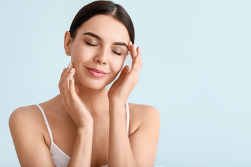 Beautiful young woman with healthy skin on color background