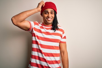 Young handsome african american man with dreadlocks wearing striped t-shirt and wool hat confuse and wonder about question. Uncertain with doubt, thinking with hand on head. Pensive concept.