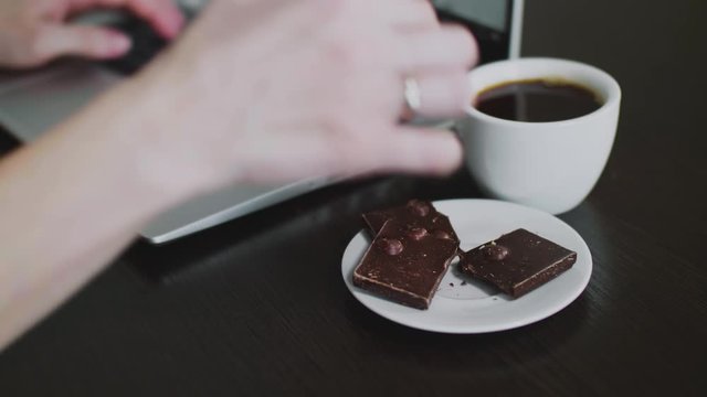 woman working and typing on the laptop and eating chokolate. Work at home