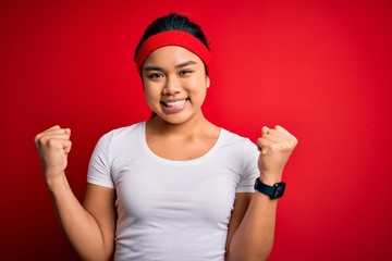 Young beautiful asian sporty woman wearing sportswear doing sport over red background celebrating surprised and amazed for success with arms raised and open eyes. Winner concept.