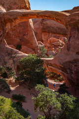 Unidentified hiker passing under Double O Arch outside Moab, Utah in Arches National Park