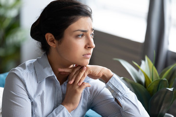 Head shot unhappy thoughtful Indian woman thinking about psychological problems close up, looking...