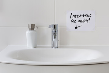 Sink with soap dispenser and note saying 