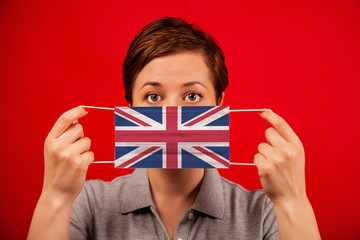 Coronavirus COVID-19 in the UK. Woman in medical protective mask with the image of the british flag.