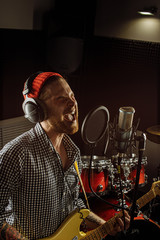 awesome caucasian musician play electric guitar and sing in recording studio. man preparing, practicing before music performance, before concert. music, instruments concept