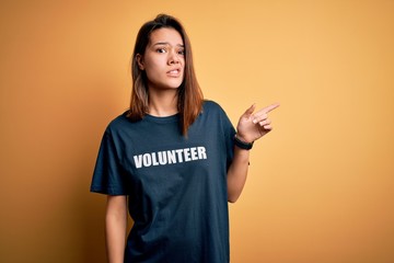 Young beautiful brunette girl doing volunteering wearing t-shirt with volunteer message word...