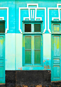 Green window frame in a green wall with fragments of green doors.