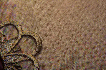 Linen brown background with lace. The thread direction is diagonal. The texture of the linen fibers.