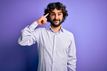 Young handsome business man with beard wearing shirt standing over purple background Smiling pointing to head with one finger, great idea or thought, good memory