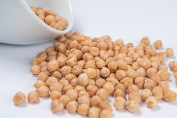 handful of Turkish peas poured out of a white cup on a white table close-up. Macro shot. Traditional food ingredients