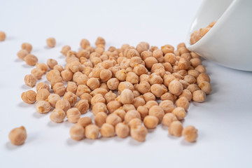 Turkish pea beans spilled out of a white cup on a white table close-up