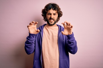 Young handsome sporty man with beard wearing casual sweatshirt over pink background smiling funny...