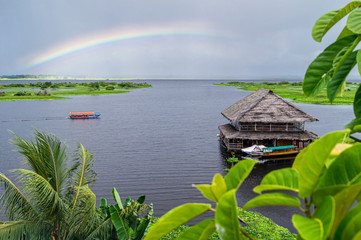 View of the Amazon River tributary in Iquitos, Peru. A rainbow over the river and a beautiful...