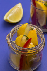 Fermented lemons with salt and chili pepper in jars.