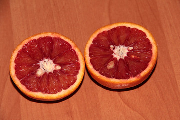 Fototapeta na wymiar Two slices of Sicilian orange on a wooden background.
