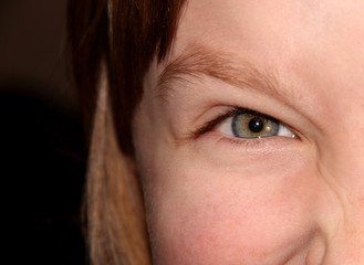 Naklejka premium An evil child's eye. Part of the child's face.