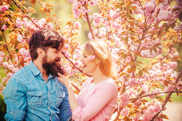 Young happy couple near blossom tree. Couple in sunny spring day. Romantic couple in love looking at each other. Happy easter.