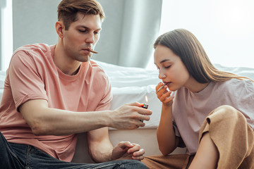 young caucasian couple, man and woman use cannabis weed, catch a buzz together at home. drugs, marijuana, hemp medicine, junkie, ganja concept