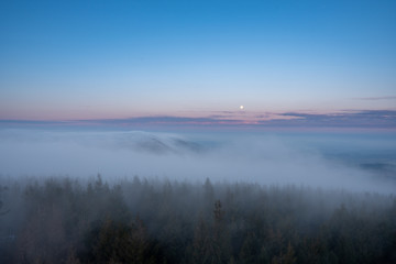 Obraz na płótnie Canvas beautiful fog in mountains before sunrise with forest with moon, Czech Beskydy