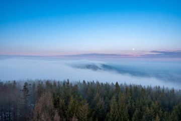 Obraz premium beautiful fog in mountains before sunrise with forest with moon, Czech Beskydy