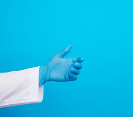 doctor’s hand is wearing a blue sterile rubber glove holding an object