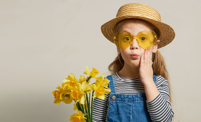 Little surprised child girl in straw hat with a bouquet of yellow flowers. Mommys little helper in the garden. Copy space for text