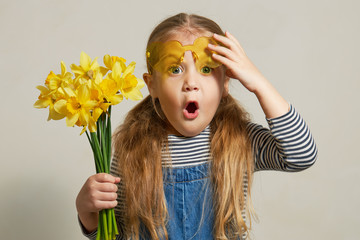 Little surprised child girl in straw hat with a bouquet of yellow flowers. Mommys little helper in...