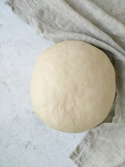Yeast dough formed into a ball close-up on a light background top view. Cooking recipe step by step.