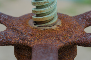 Close up shot of an aged and rusty threaded rod on an old vintage machine with control wheel. Concept of traditional industry.