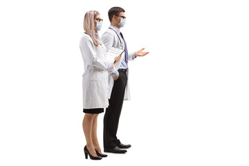 Male and female doctor with a clipboard wearing medical masks