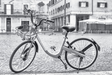 Fototapeta na wymiar Black and white photo of a bicycle ready for sharing on the empty Navona Square in Rome. Italy. All potential trademarks are removed.