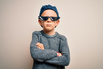 Young little caucasian kid wearing internet meme thug life glasses over isolated background skeptic and nervous, disapproving expression on face with crossed arms. Negative person.