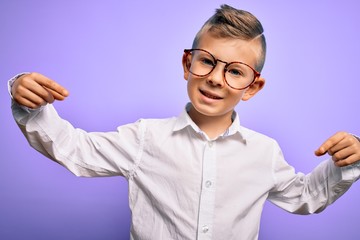 Young little caucasian kid with blue eyes wearing glasses and white shirt over purple background looking confident with smile on face, pointing oneself with fingers proud and happy.
