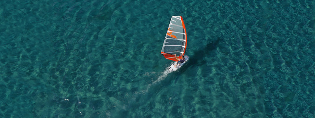 Aerial drone ultra wide photo of wind surfer cruising in high speed in tropical exotic bay