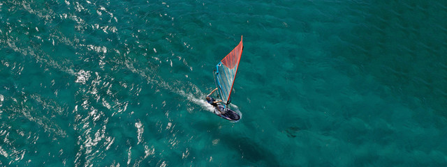 Aerial drone ultra wide photo of wind surfer cruising in high speed in tropical exotic bay