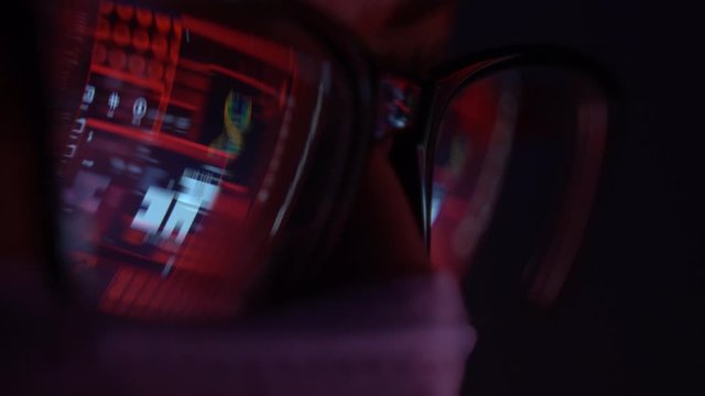 masked man in front of a computer ,the reflection in the glasses