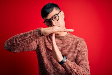 Young handsome hispanic man wearing nerd glasses over red background Doing time out gesture with...