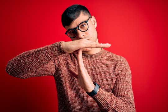 Young handsome hispanic man wearing nerd glasses over red background Doing time out gesture with hands, frustrated and serious face
