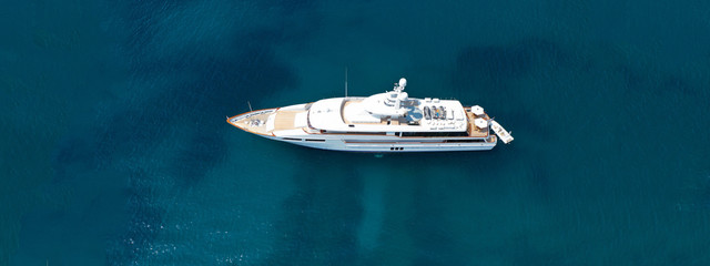 Aerial drone top down photo of luxury yacht with wooden deck anchored in open ocean sea - obrazy, fototapety, plakaty