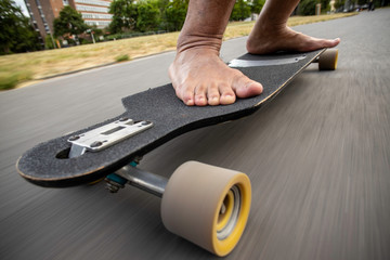 barefoot man skateboarding in asphalt, foot close up