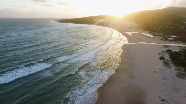 Aerial shot of some waves rolling on to a beach during sunset in Tarifa 4K