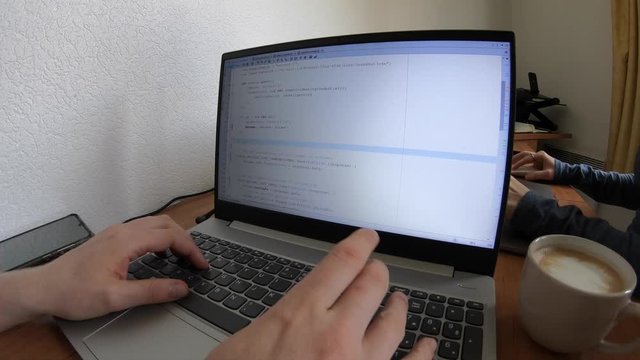 Working From Home on Laptop Coding in NodeJS, Javascript With Cappuccino to Drink While Working