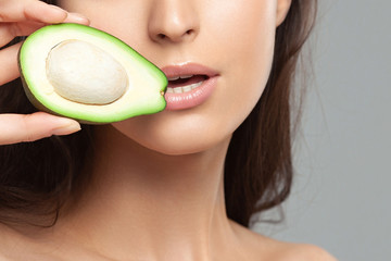 Young beautiful woman holding avocado