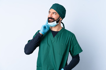 Surgeon man in green uniform over isolated background thinking an idea while looking up