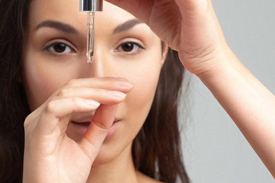 Young Beautiful Woman With Clean Perfect Skin Uses Age-sensitive Serum In Pipette